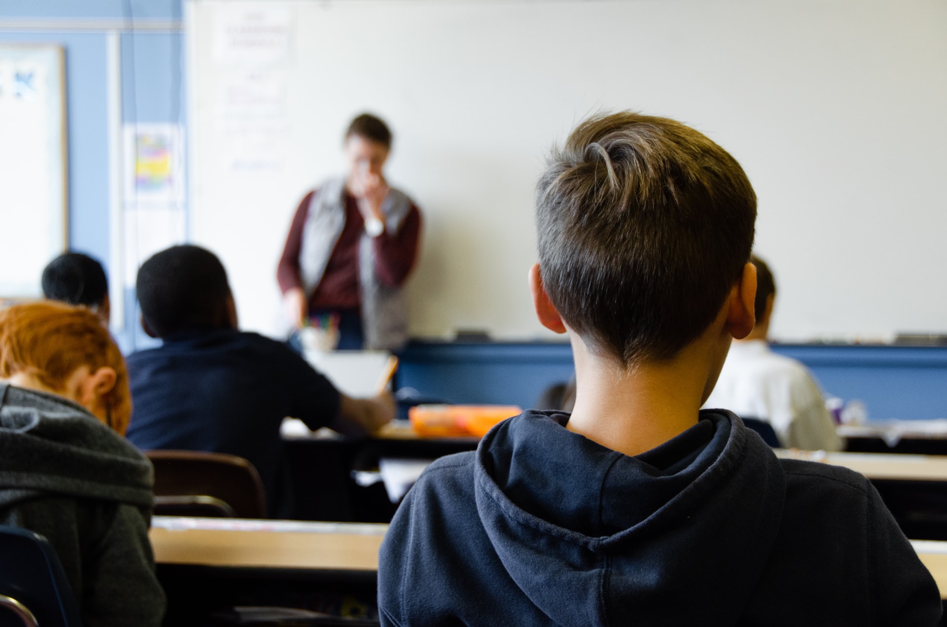 Alumno de espaldas atendiendo a explicaciones del profesor