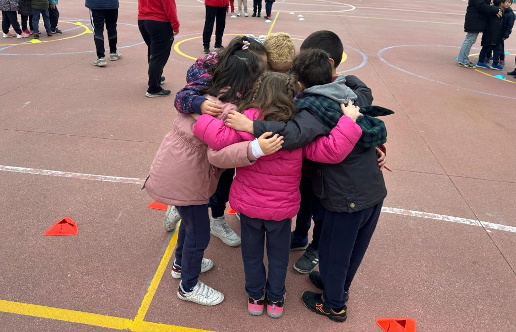 Un grupo de alumnos/as de Infantil se abraza en la pista del patio
