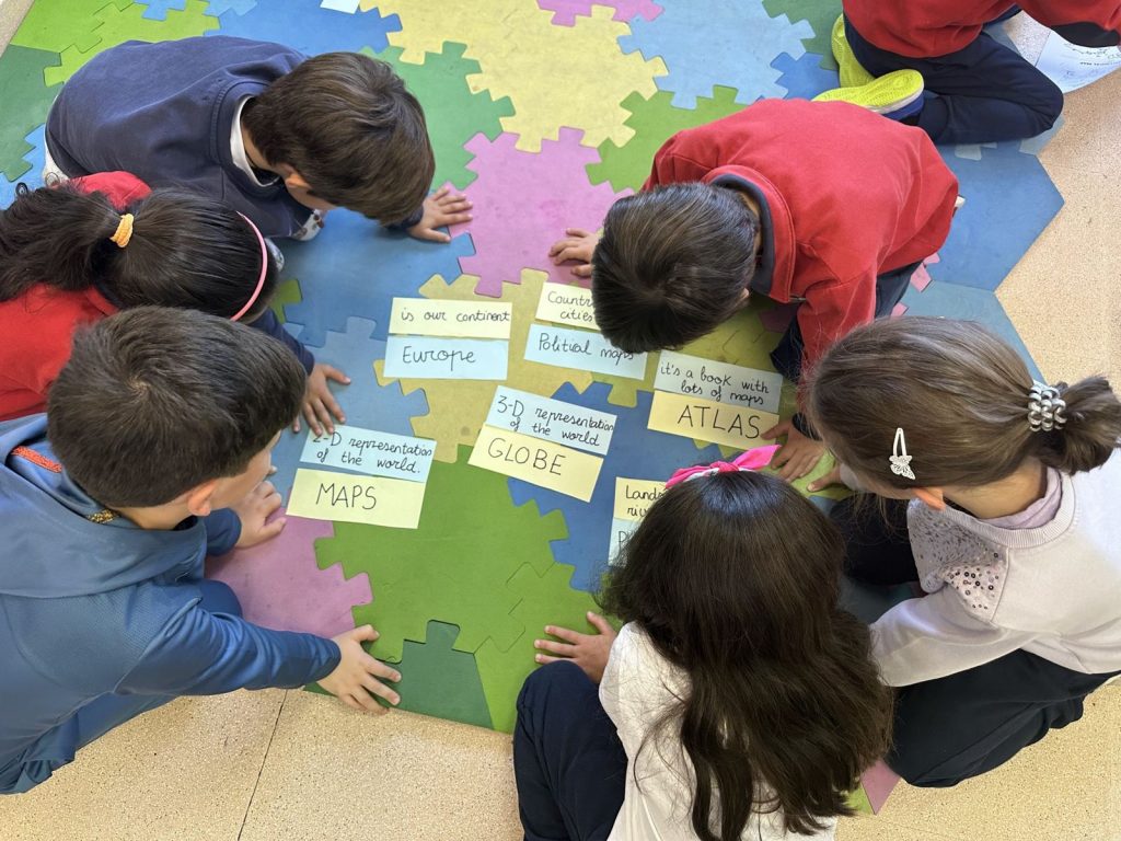 Alumnos/as colocan tarjetas en inglés sobre una alfombra de puzle
