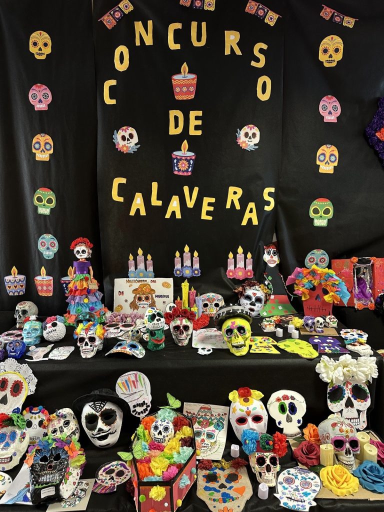 Altar del concurso de calaveras con máscaras pintadas, flores y velas