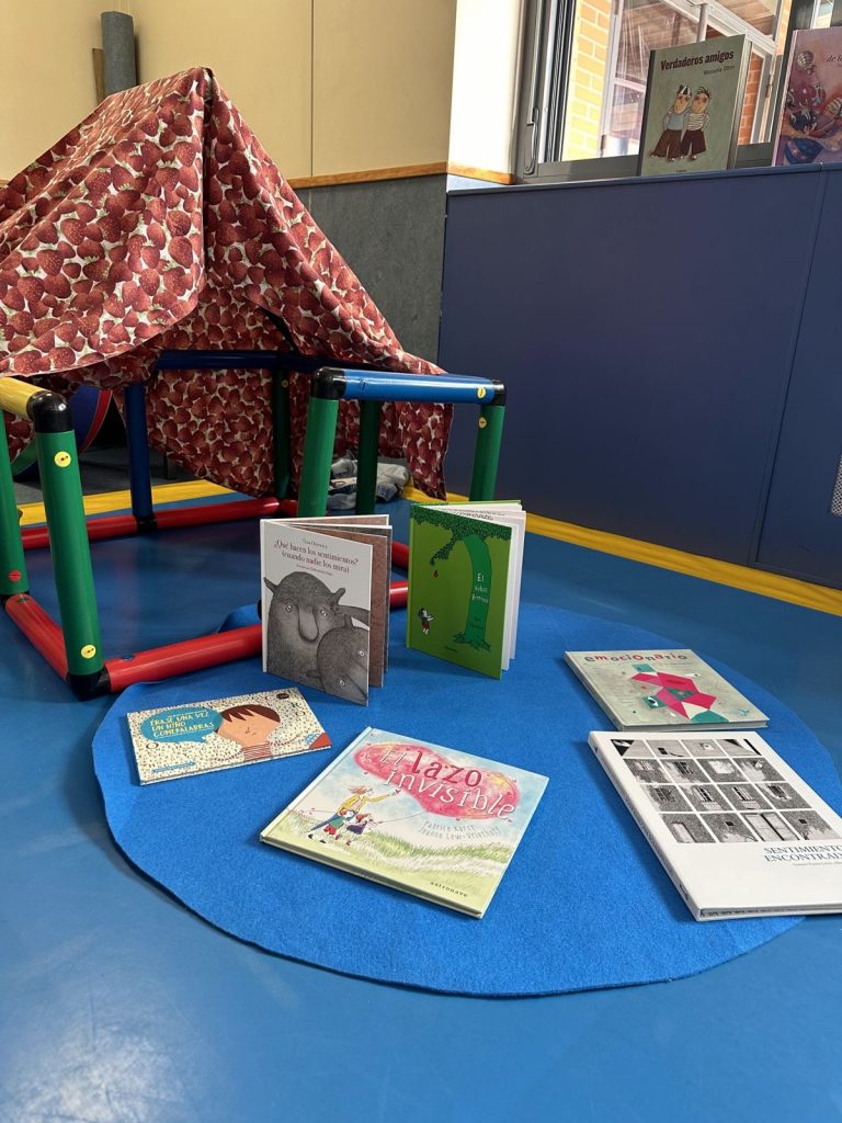 Rincón de cuentos de Infantil con una casita de tela, una alfombra azul y libros abiertos