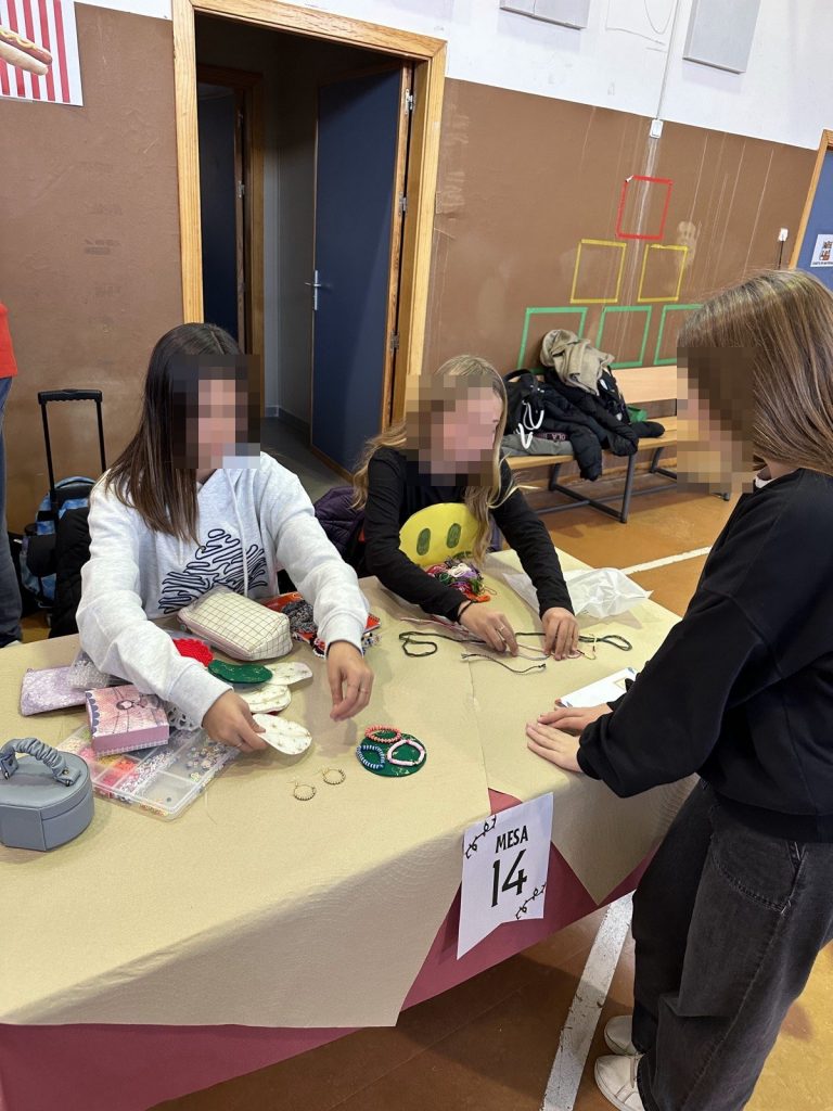 Alumnas preparando pulseras en su mesa del mercadillo