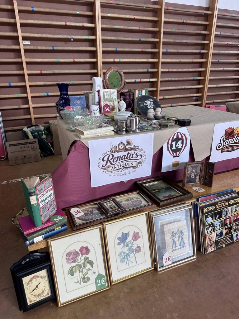 Mesa de antigüedades con cuadros de flores, jarrones y libros