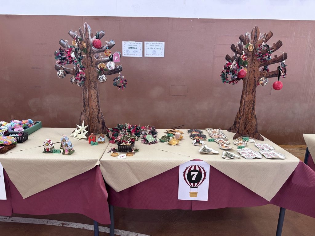 Mesa del mercadillo con dos árboles de cartón decorados y adornos hechos a mano