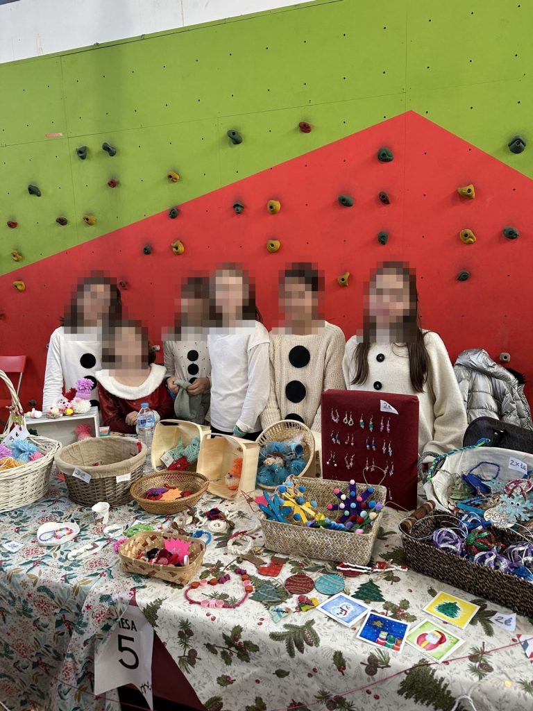 Alumnas disfrazadas de muñeco de nieve en su mesa del mercadillo