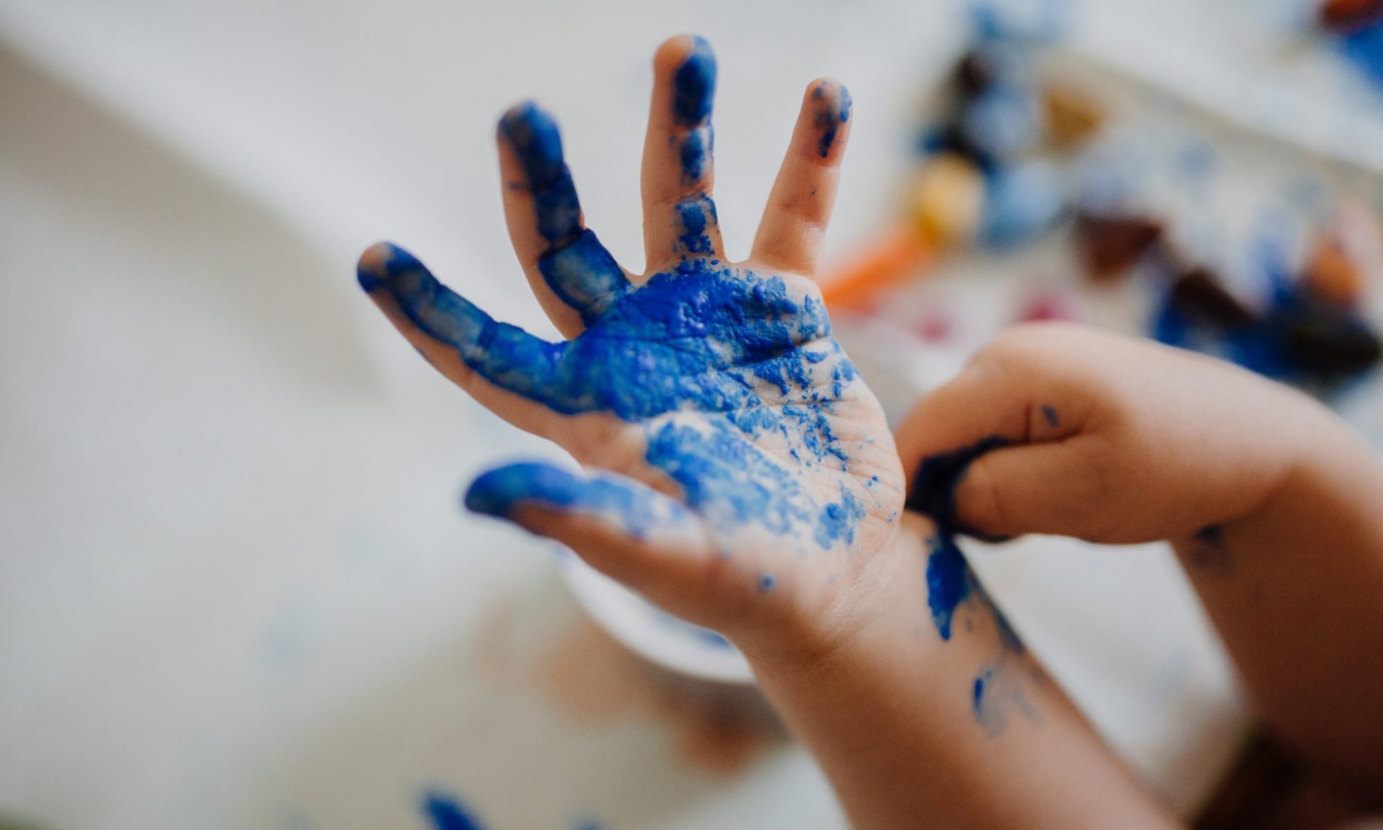 una mano de niño pintada con pintura azul