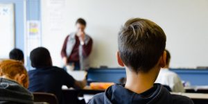 Alumno de espaldas atendiendo a explicaciones del profesor