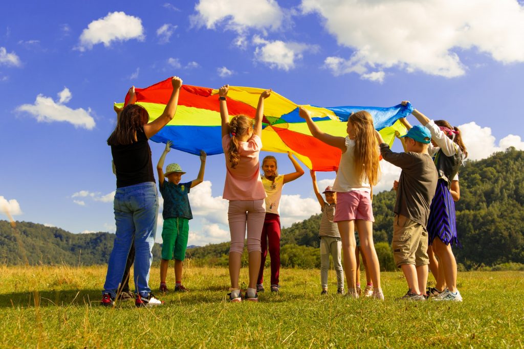 Varios niños jugando y sosteniendo una bandera de colores