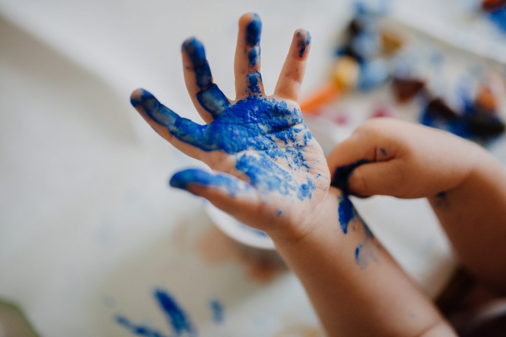 una mano de niño pintada con pintura azul
