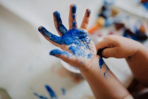 una mano de niño pintada con pintura azul