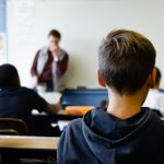 Alumno de espaldas atendiendo a explicaciones del profesor
