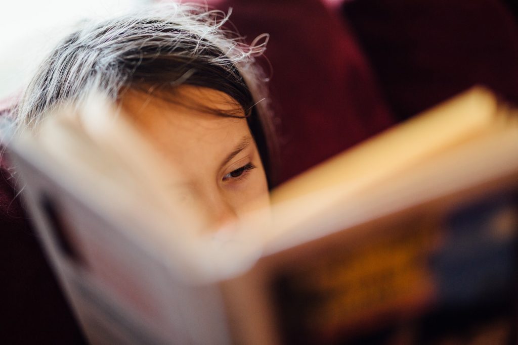 Niña leyendo, sólo se ve la cara y un libro difuminado