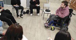 Un alumno de la Universidad Rey Juan Carlos con discapacidad motriz dirige una actividad realizada por alumnos del IES Palomeras-Vallecas en la que tienen que escribir con su mano no dominante.