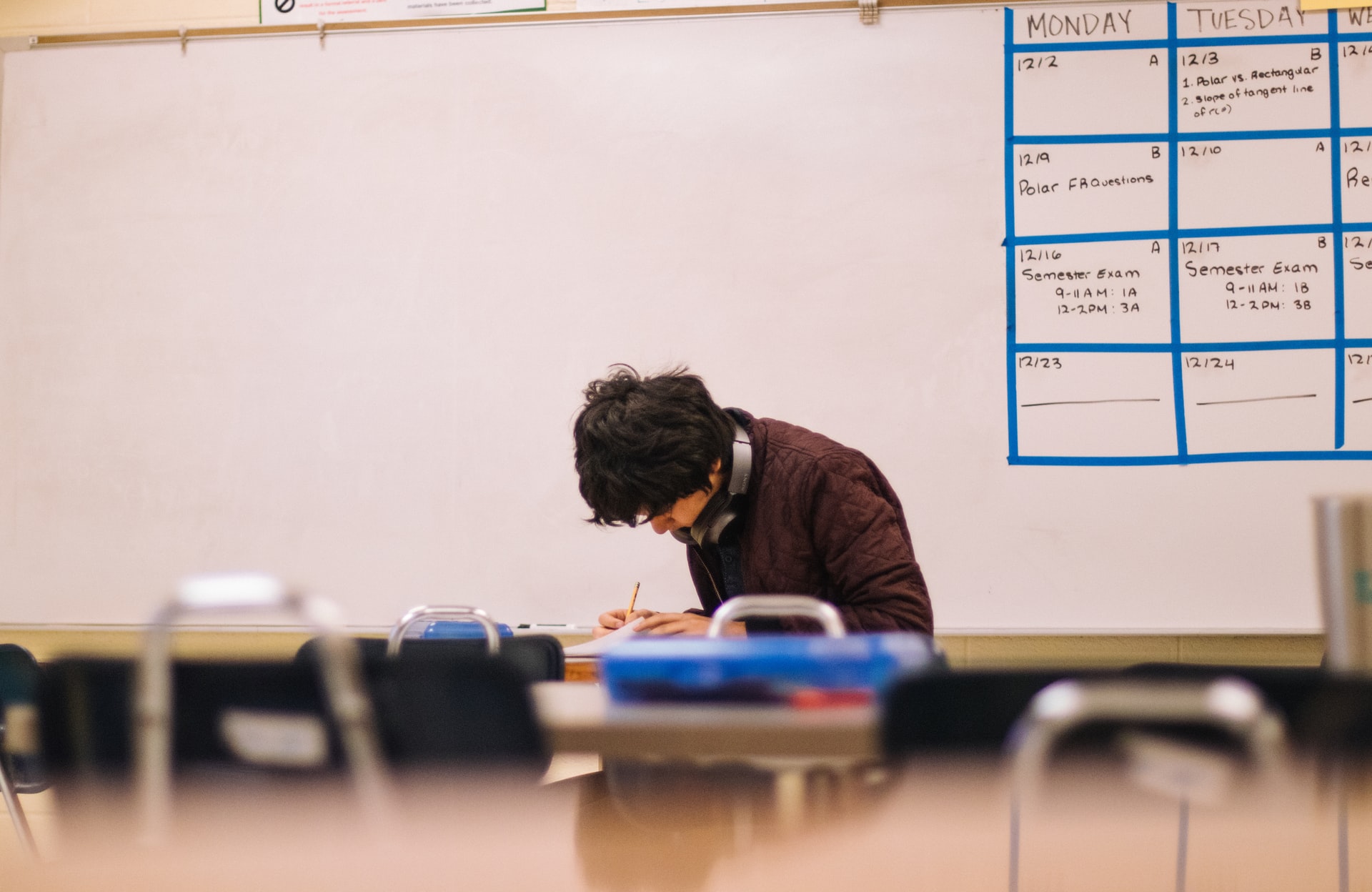 un alumno escribiendo sobre mesa de escritorio en aula
