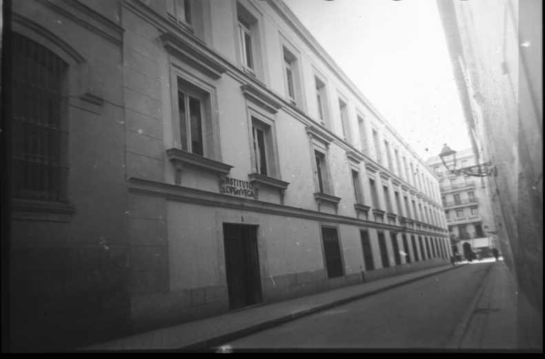 Fotografía en blanco y negro. Se ve la fachada lateral del edificio, al fondo la calle San Bernardo.